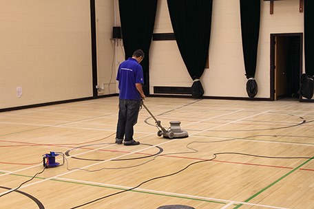 Man using floor sander on a gym floor in London