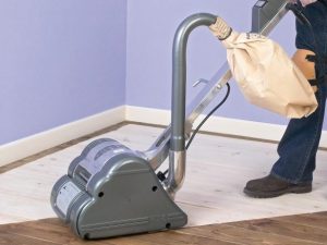 Drum sander in use on half sanded hardwood floor