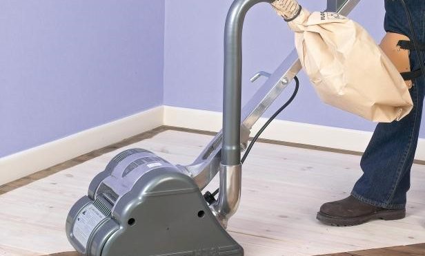 Drum sander in use on half sanded hardwood floor