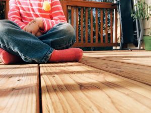 child sat on sanded wooden deck