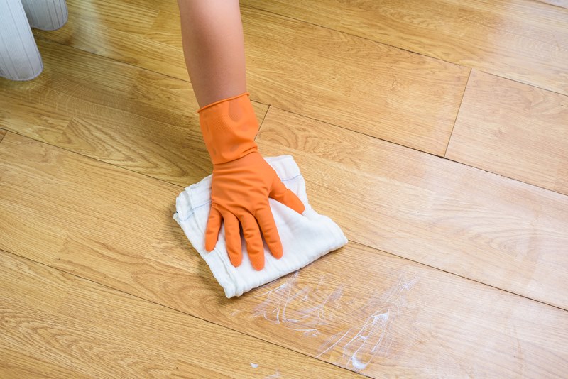 Hand in gloves cleaning Wooden floor with rag and cleanser at home. housework and housekeeping concept