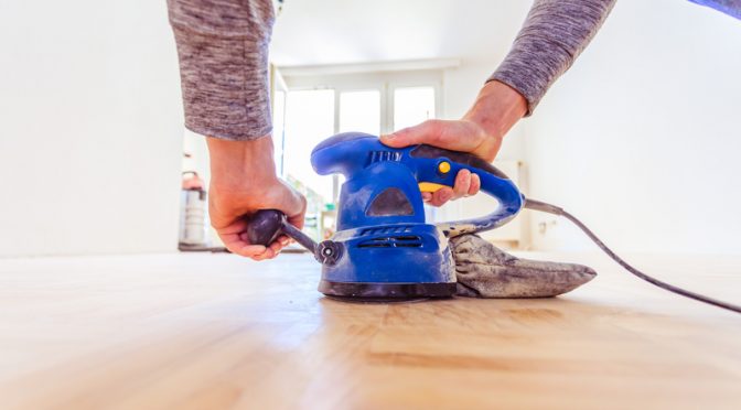 man sanding his wooden floor