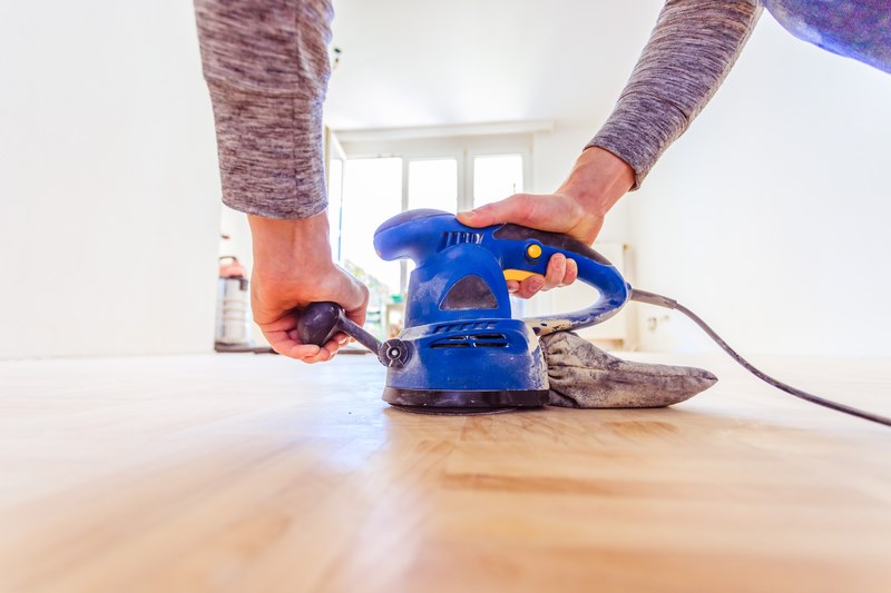 man sanding his wooden floor